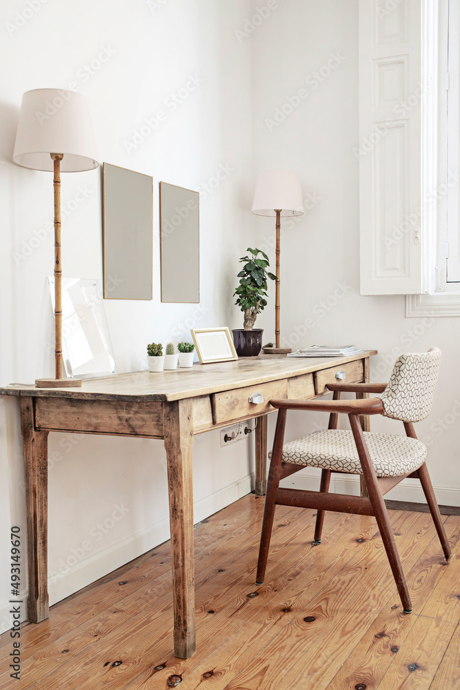 带配套椅子、双灯、植物和松木地板的仿古木制书桌
