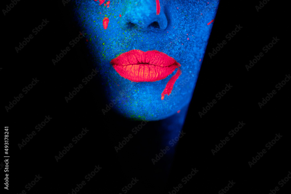 发光的嘴唇。一张年轻女子脸上涂着霓虹灯的照片。