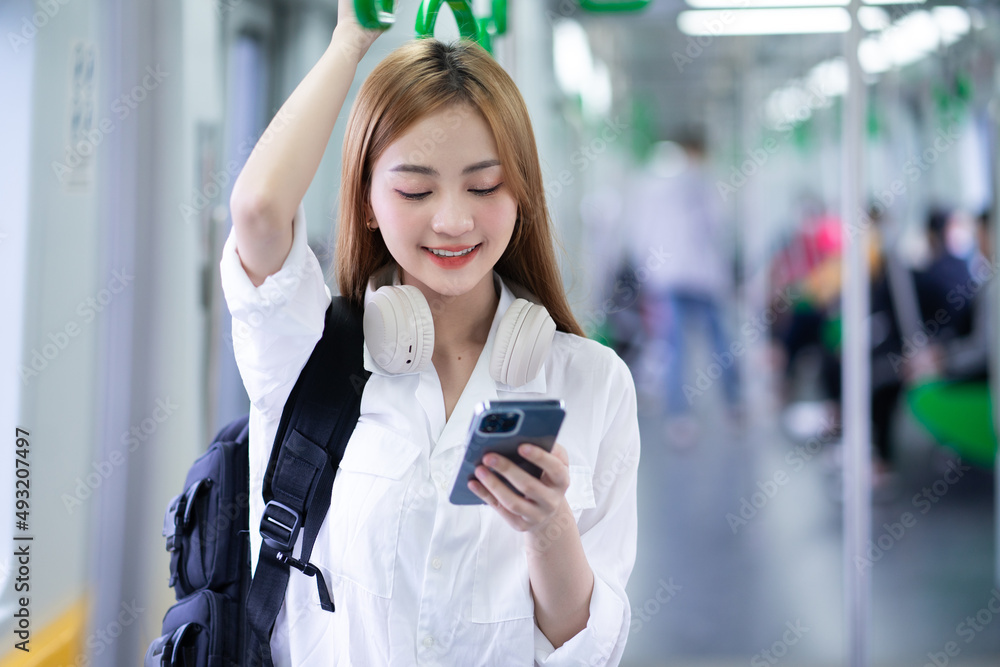 年轻亚洲女性在地铁上使用智能手机的照片