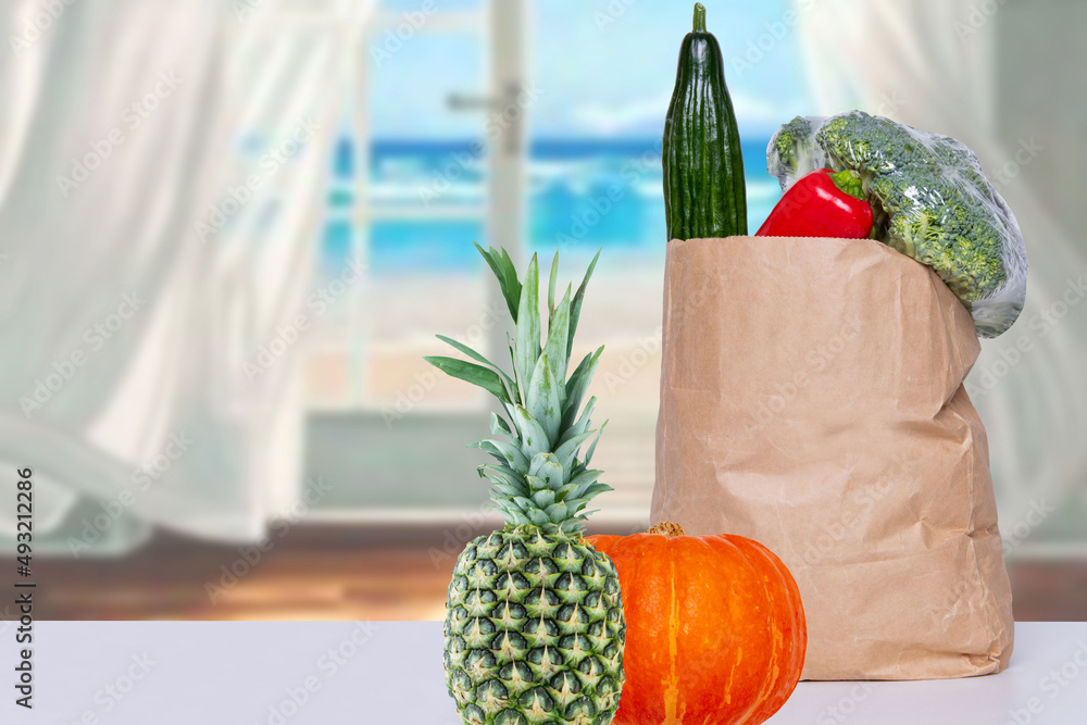 餐桌上放着新鲜蔬菜、南瓜和菠萝的棕色购物袋特写