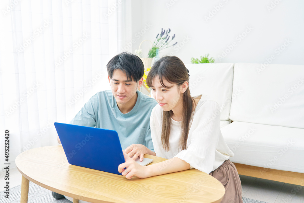 ノートパソコンを使うカップル　リビング