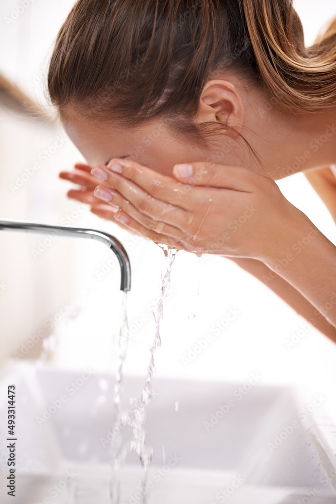 美丽的皮肤始于洗涤。一位年轻女子在水槽上洗脸的特写镜头。