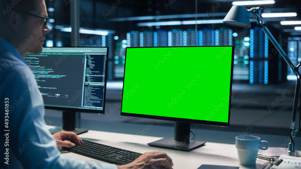 Male Specialist Working on Desktop Computer with Green Screen Mock Up Display in Evening Creative Of