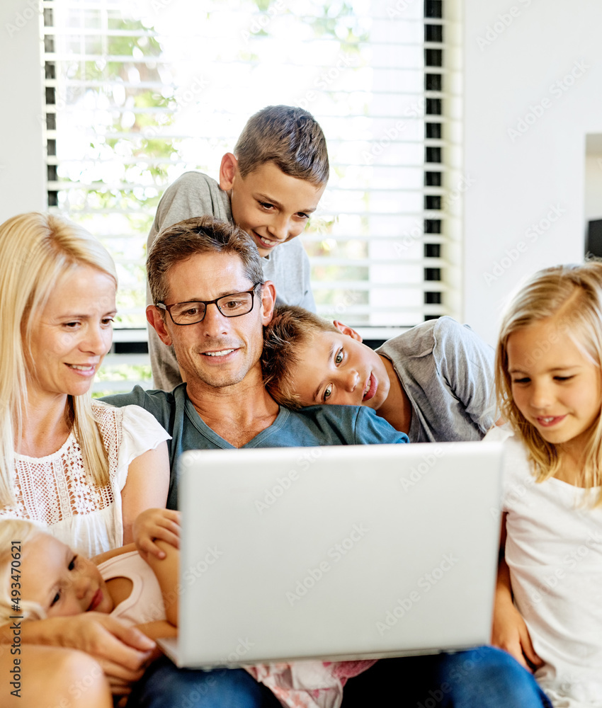 向他们的孩子介绍网络世界。一家人在家一起使用笔记本电脑的照片。