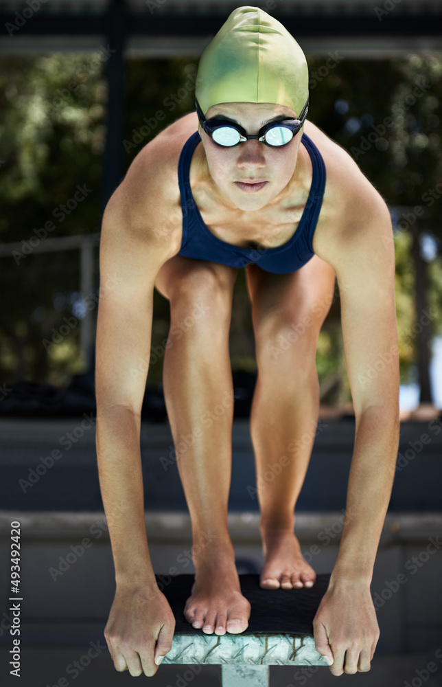 准备好获胜。领奖台上的一名游泳运动员准备好跳水。