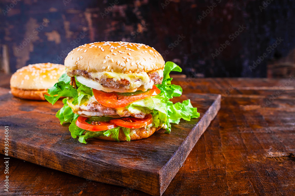 美味的新鲜自制汉堡特写，在乡村的木头上放上生菜、奶酪、洋葱和番茄