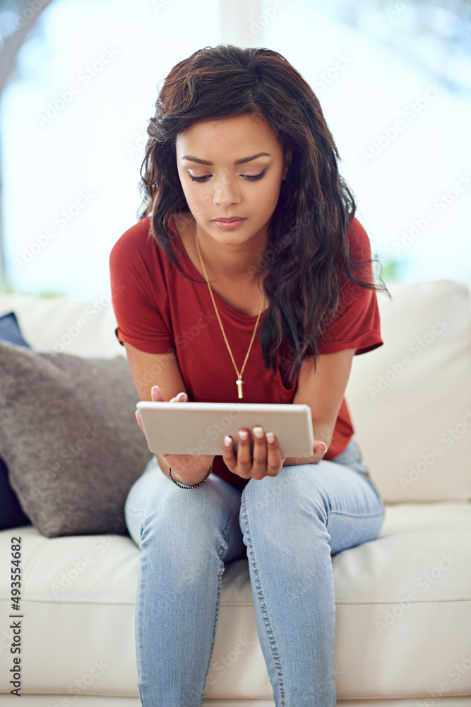 用她的技术放松。一个年轻女人在家放松时使用平板电脑的裁剪镜头。
