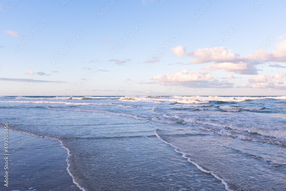 日落时海滩上的巨浪，日落的海洋地平线，蓝天白云