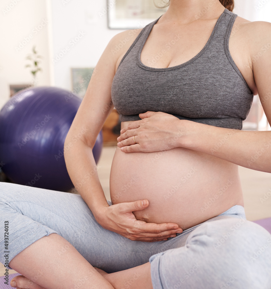 为宝宝保持身体健康。孕妇在家锻炼的裁剪镜头。