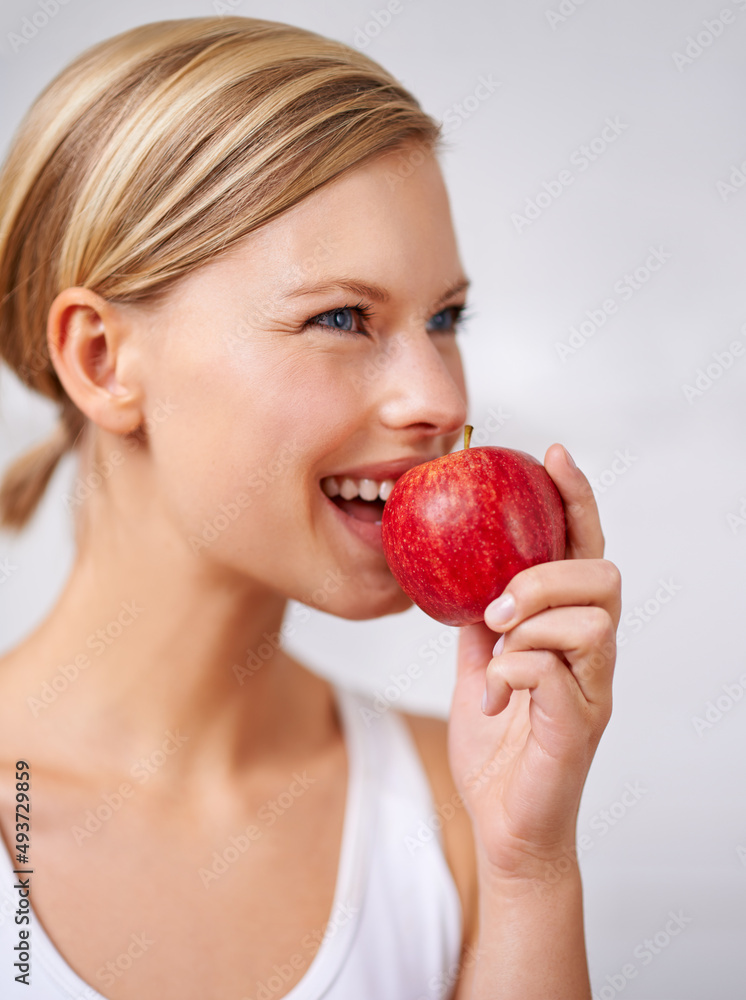 So fresh and delicious. A cropped shot of a beautiful young woman eating a delicious red apple.