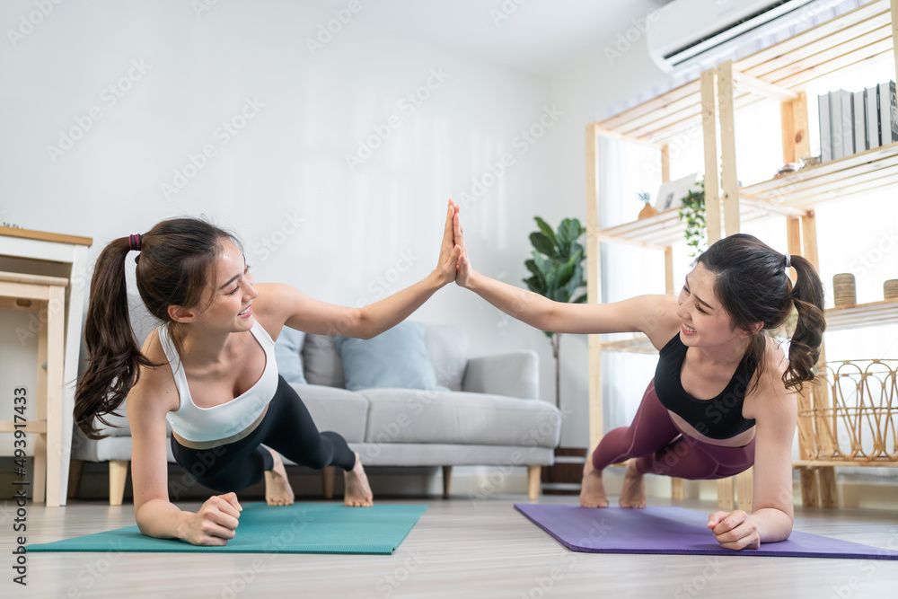 亚洲活跃女性朋友在家一起做瑜伽普拉提锻炼。