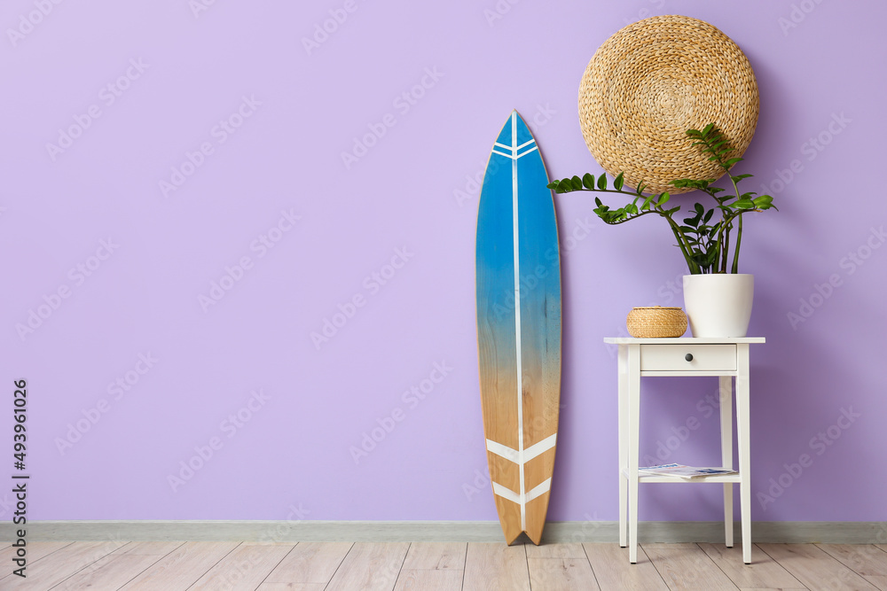Interior of room with surfboard and table near color wall