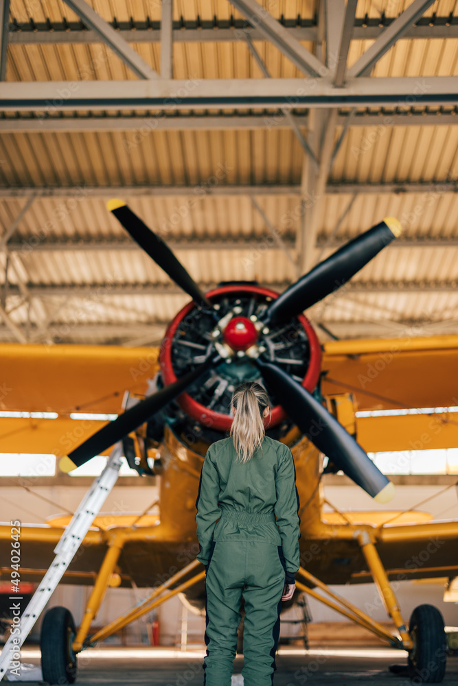 一位金发女飞行员望着飞机螺旋桨的远距离镜头。