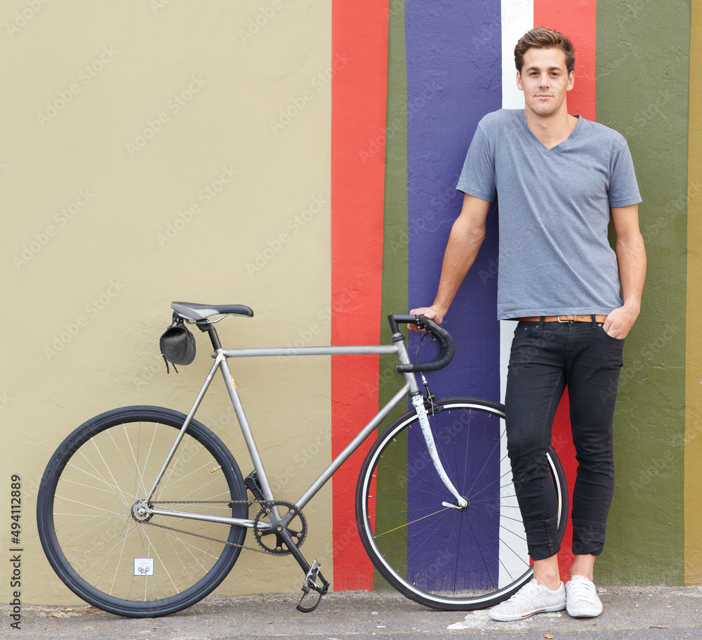 想去兜风。一个时髦的年轻人骑着自行车站在外面的照片。