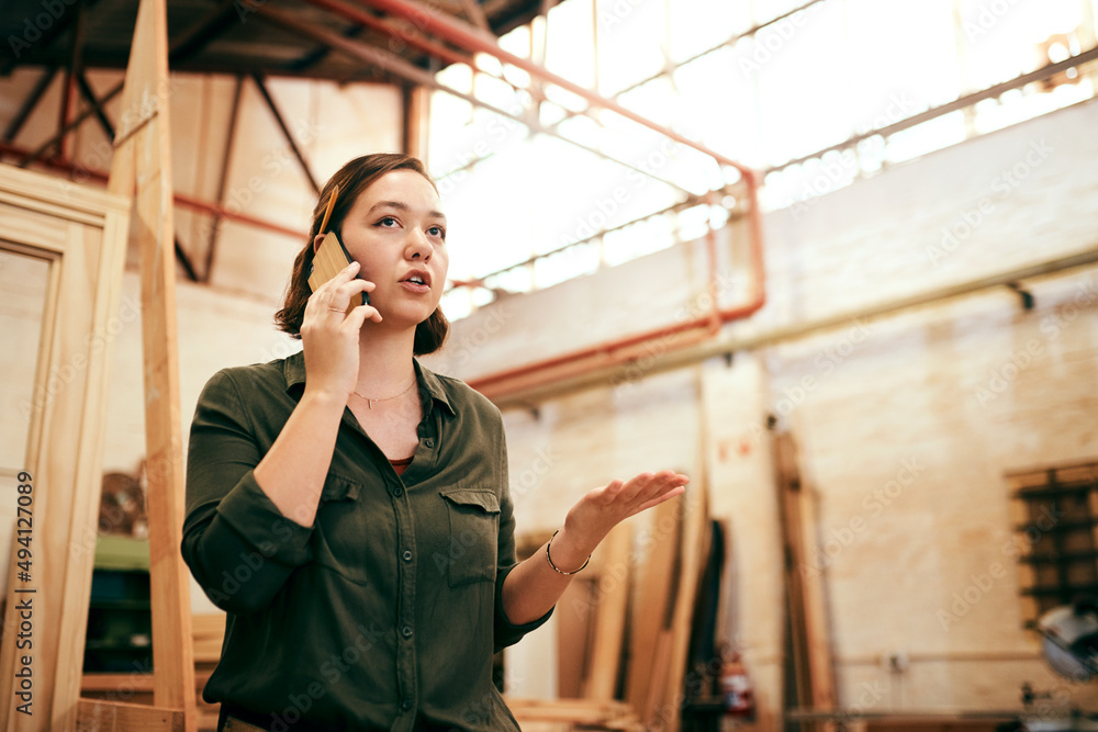 Im always gettin new orders. Shot of a female carpenter talking on her cellphone while standing in h