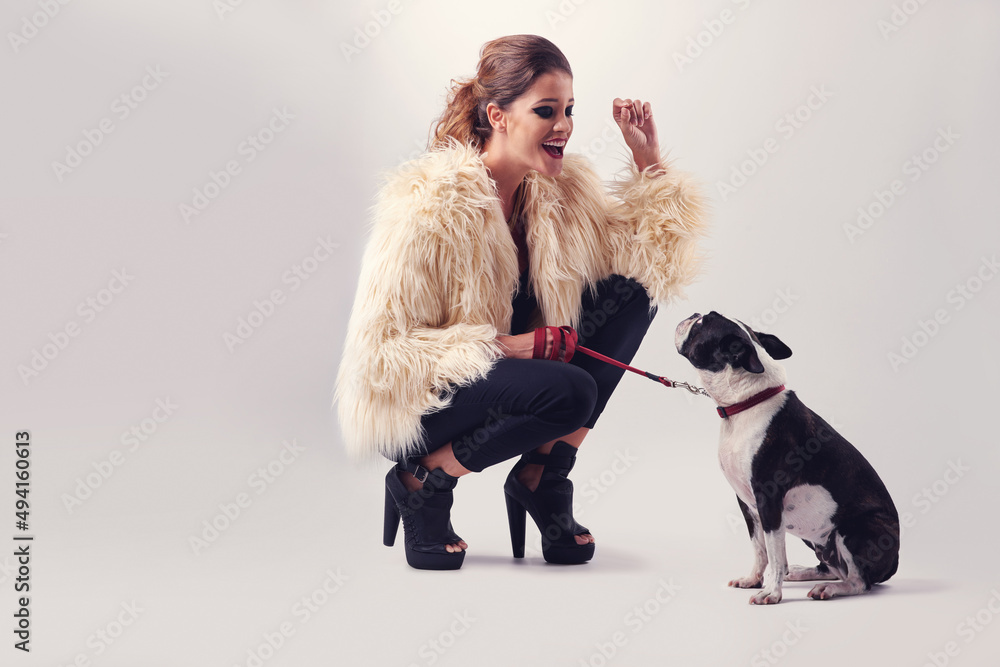 Thats a good boy. Studio shot of a young woman posing with her dog against a grey background.