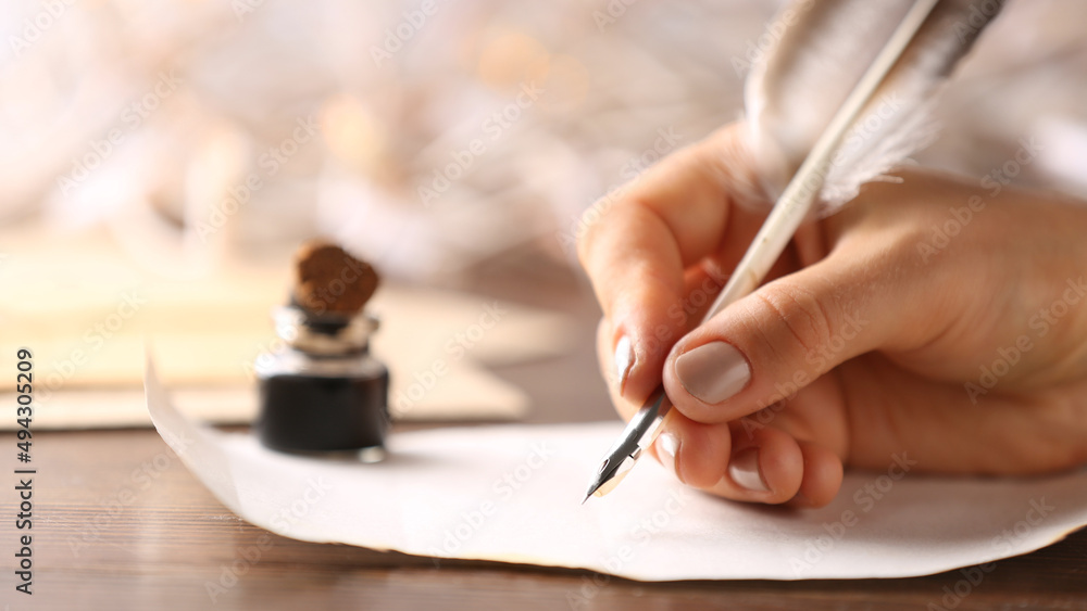 女人在桌子上用墨水在纸上写字，特写