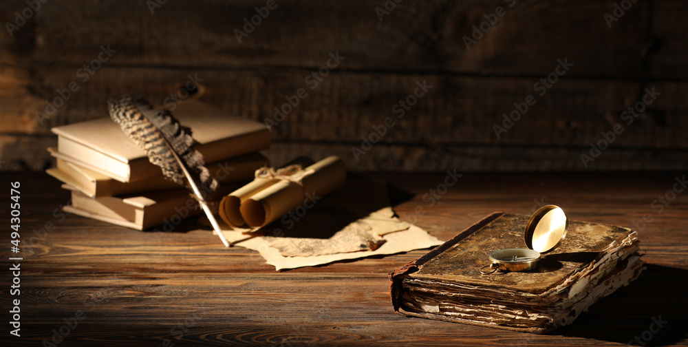 木桌上有指南针、羽毛和卷轴的旧书