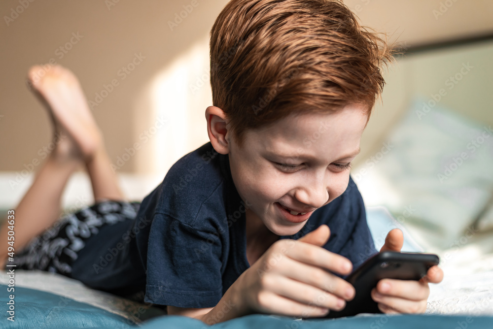 红头发男孩手里拿着手机，看动画片和电子游戏。生活方式