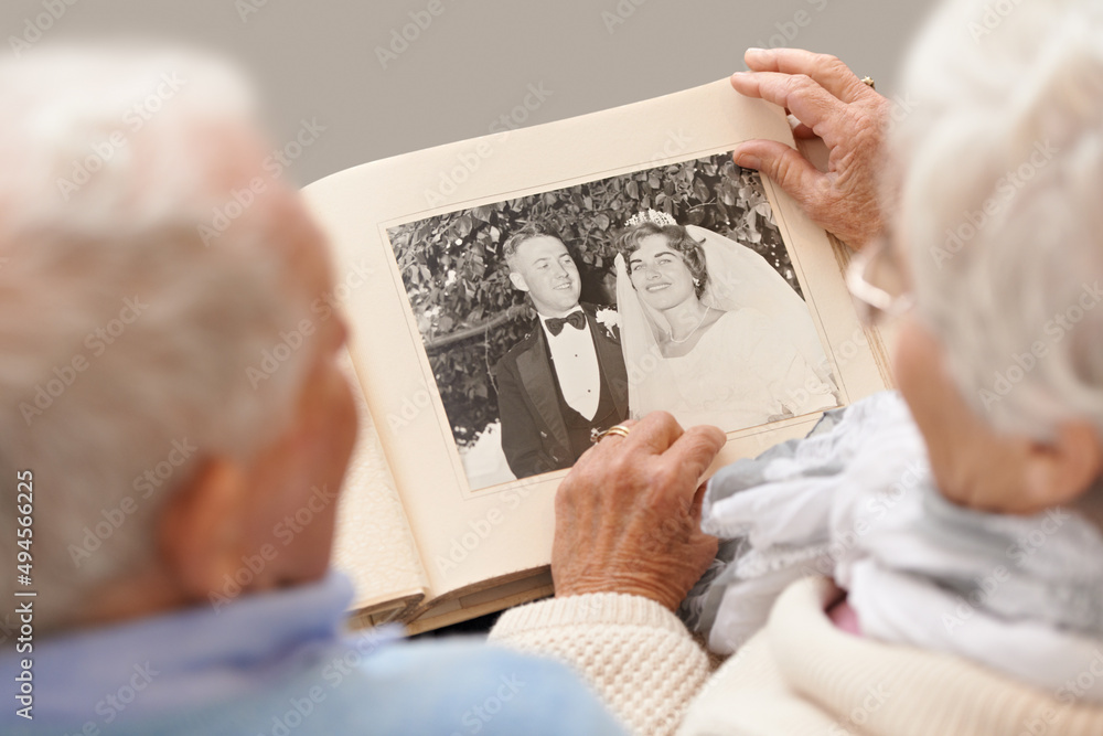 回忆起来就像昨天一样。一对资深夫妇翻阅结婚相册的照片。