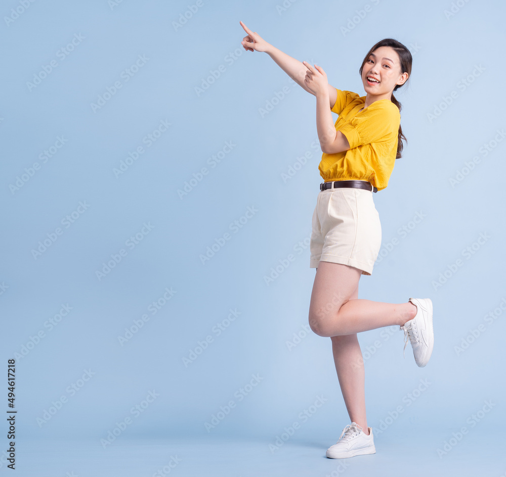 Full length image of young Asian woman posing on blue background