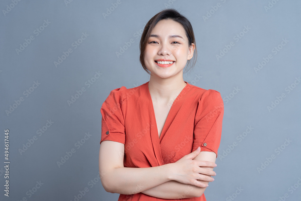 年轻的亚洲女性在灰色背景下摆姿势
