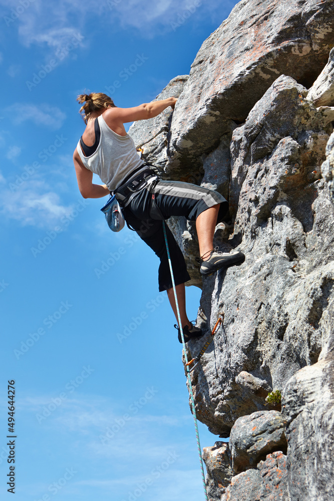 肾上腺素正将她推向顶峰。一名年轻女子在被陷害的情况下爬上岩石表面