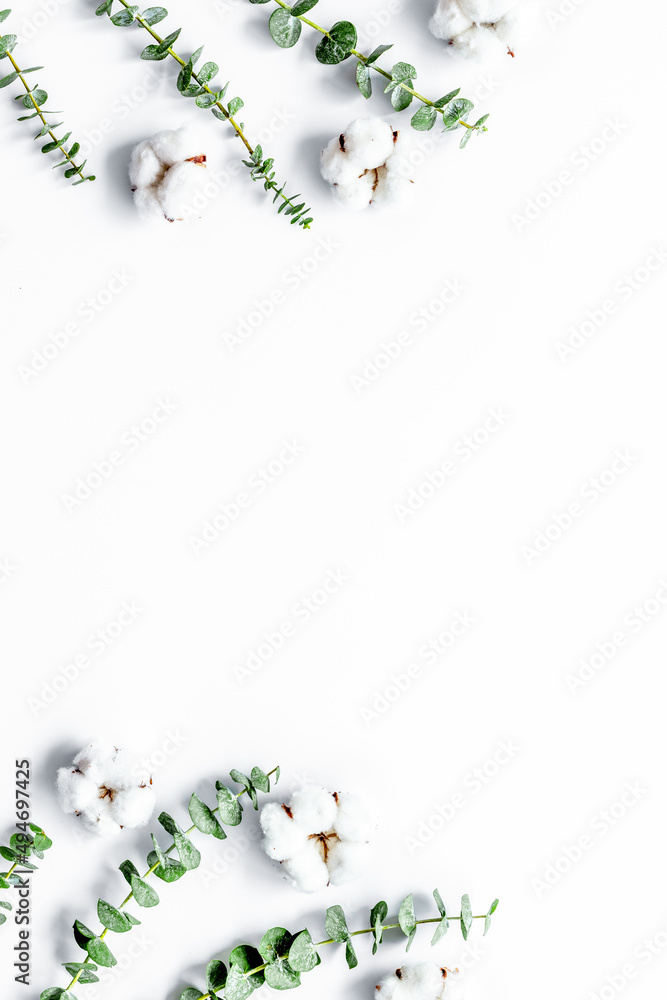 Flowers composition on white desk with fresh eucalyptus branches and cotton. Flat lay, top view, cop