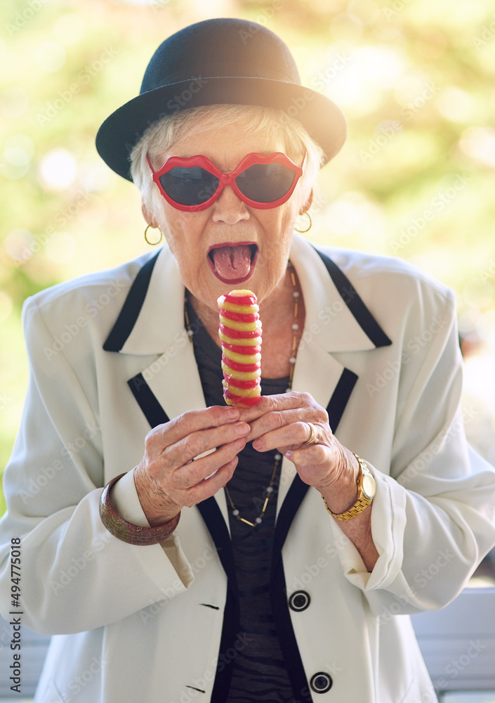 她内心的孩子渴望冰淇淋。一位喜欢玩乐的老年妇女在外面吃冰淇淋的画像
