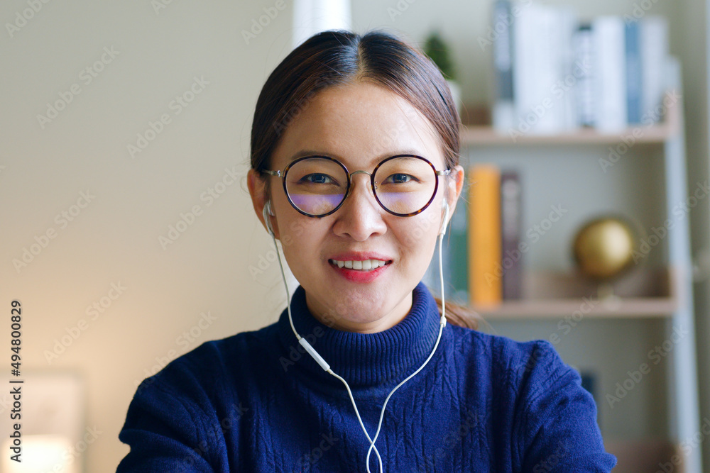 Young Asian woman creator wearing glasses and headphone talking on video call conference or virtual 