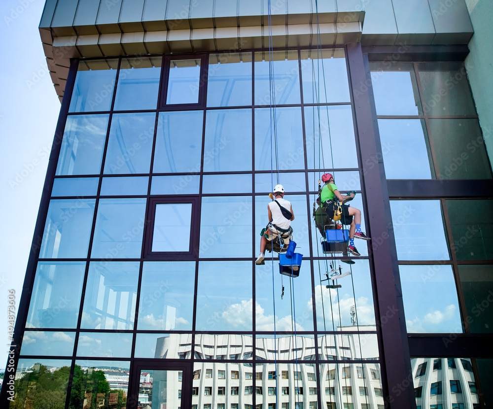 工业登山工人清洗高层建筑的玻璃窗，悬挂在安全绳上