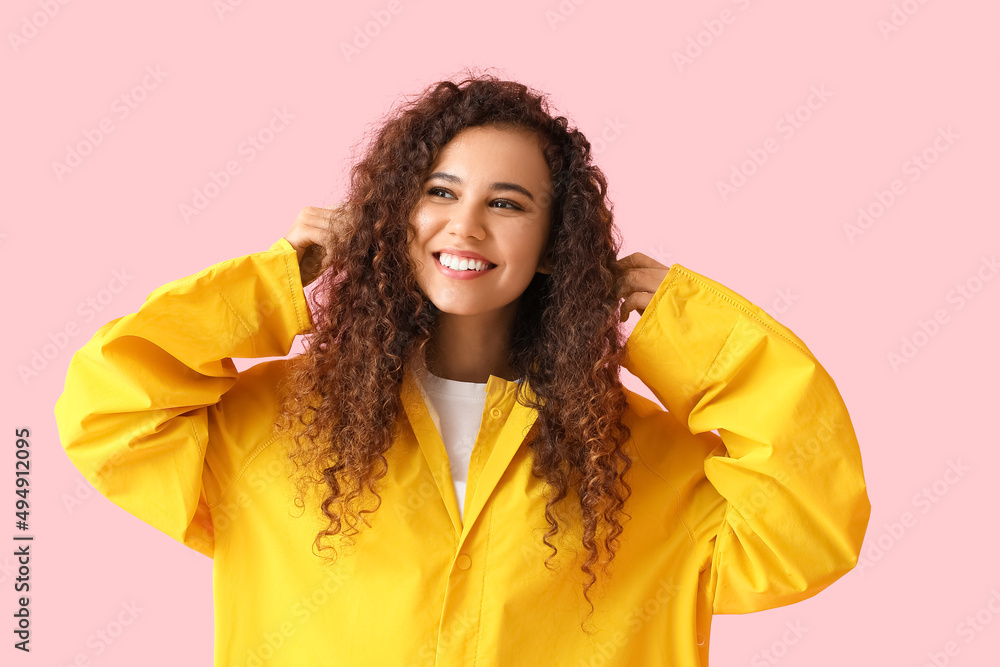 微笑的年轻非裔美国女性，身穿黄色雨衣，粉色背景
