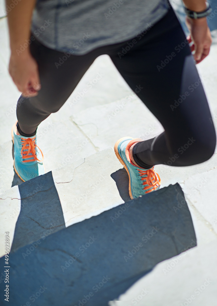 加强她的健身计划。一个运动型年轻女子站在外面台阶上的裁剪镜头。