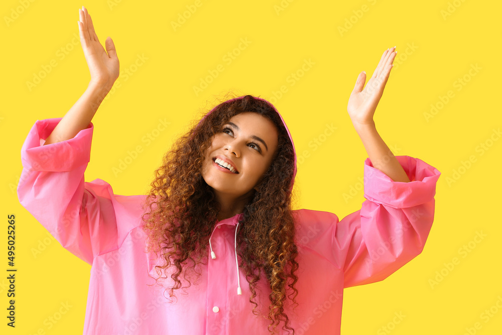身穿黄色背景粉色雨衣微笑的年轻非裔美国妇女