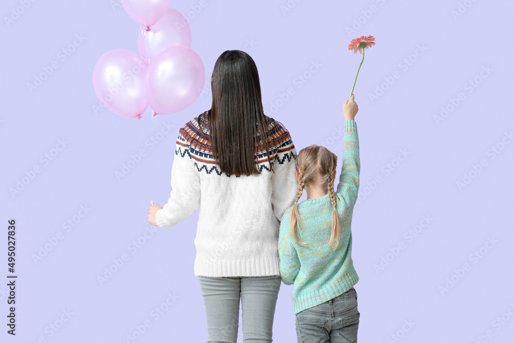 小女孩和她的妈妈穿着淡紫色背景的气球保暖毛衣