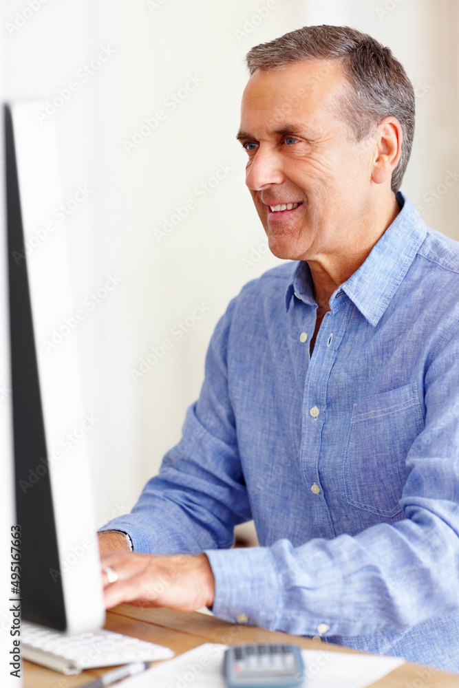 微笑的成熟男人用电脑计算开支。微笑的成熟男子计算的肖像