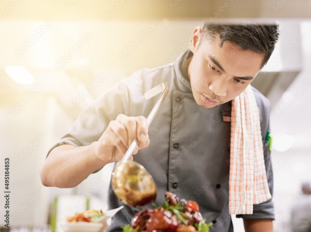 最后一笔。一个年轻男厨师在厨房做饭的裁剪镜头。