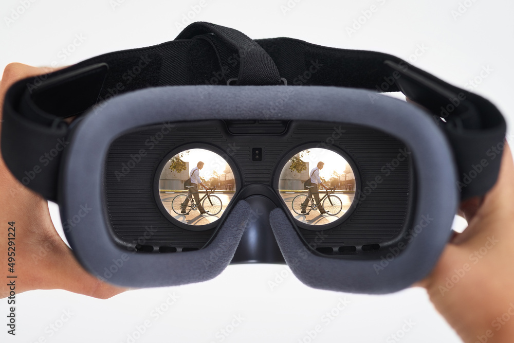 虚拟现实时代已经到来。一个人拿着VR耳机与一名骑自行车的男子合影