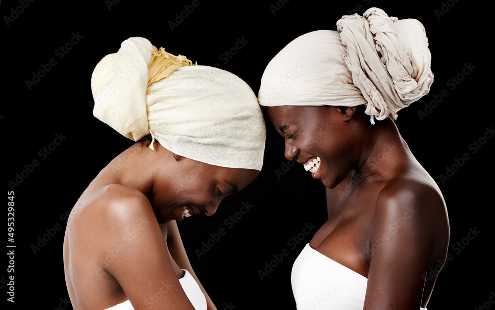 Live, love and laugh. Studio shot of two beautiful women wearing headscarves against a black backgro