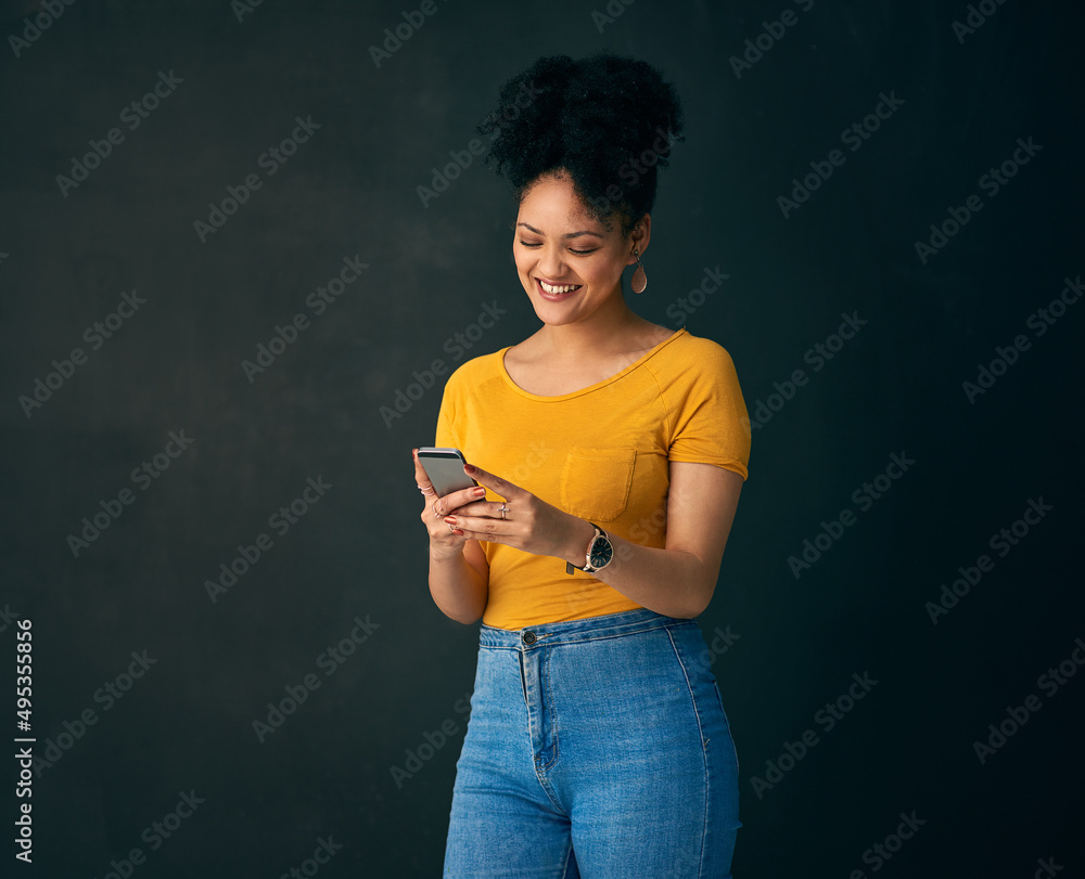 传播一些微笑表情符号。一名年轻女子拿着手机对着灰色衣服摆姿势的照片