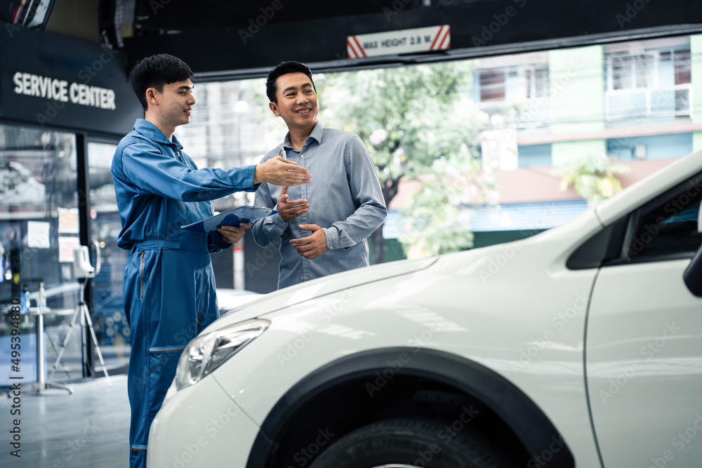 亚洲汽车修理工在车库向客户解释汽车状况。