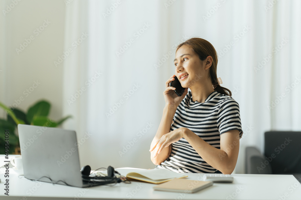 亚洲年轻快乐的女人在家里，在家里的办公室，用笔记本电脑聊天