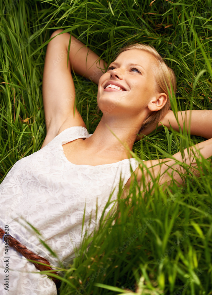 放松的天性，平静的拥抱。一个迷人的年轻女人躺在开阔的绿地上。
