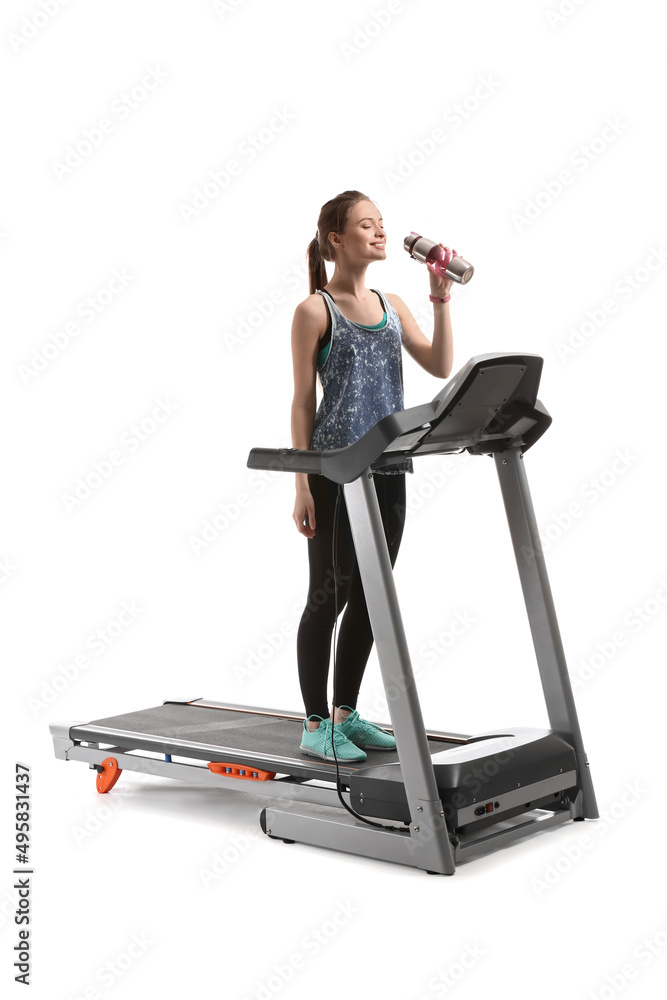 运动型年轻女子在白色背景下在跑步机上训练后喝水