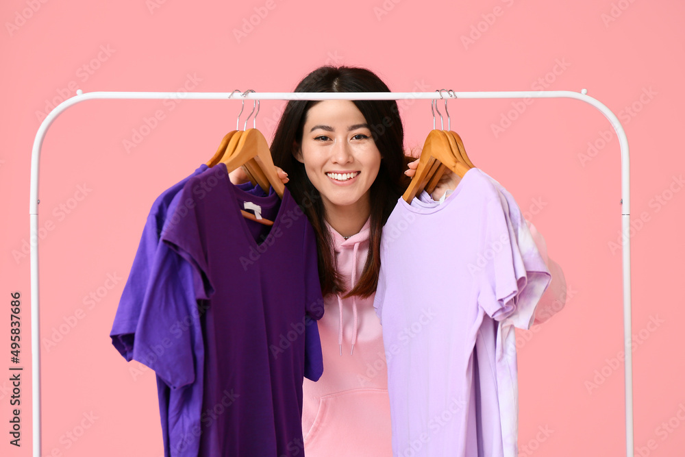年轻的亚洲女人和粉色背景t恤的架子
