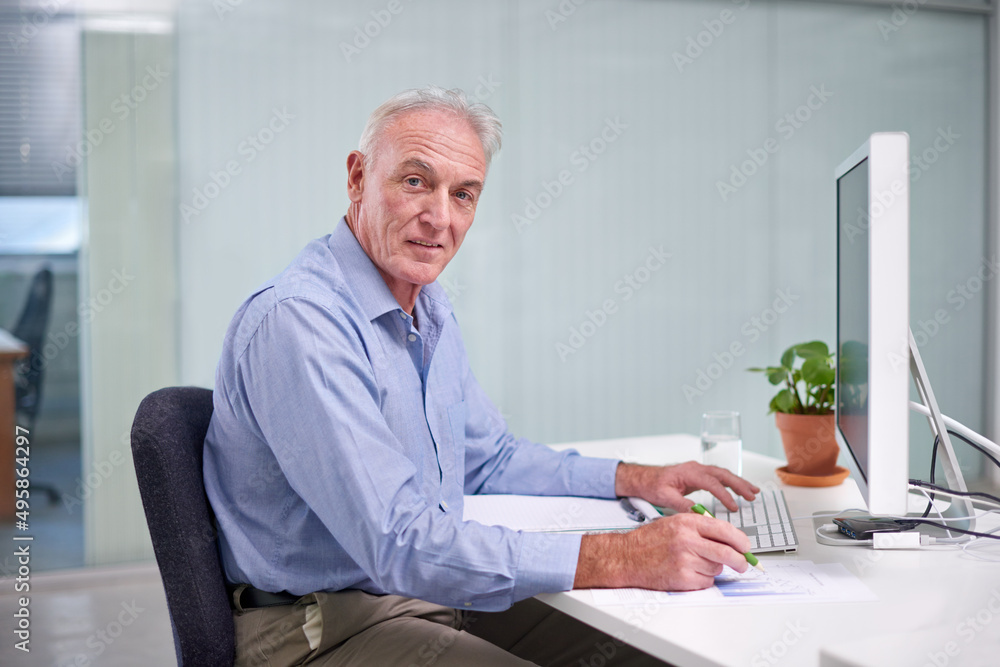 Experience is his most valuable asset. Portrait of a mature businessman working at his office desk.