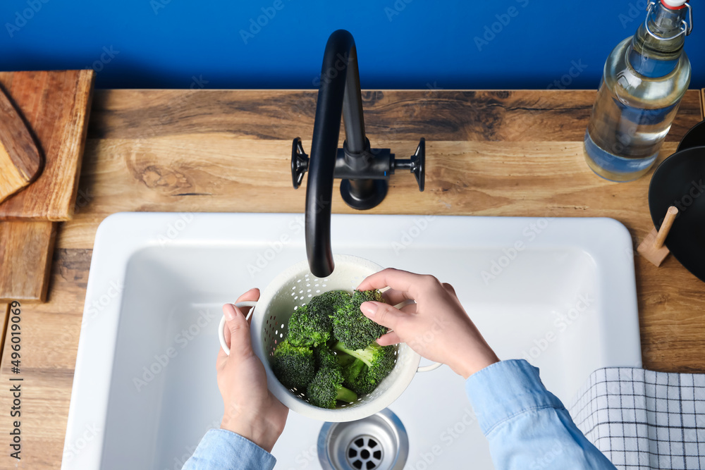 女人在水槽上用漏勺清洗新鲜西兰花，特写