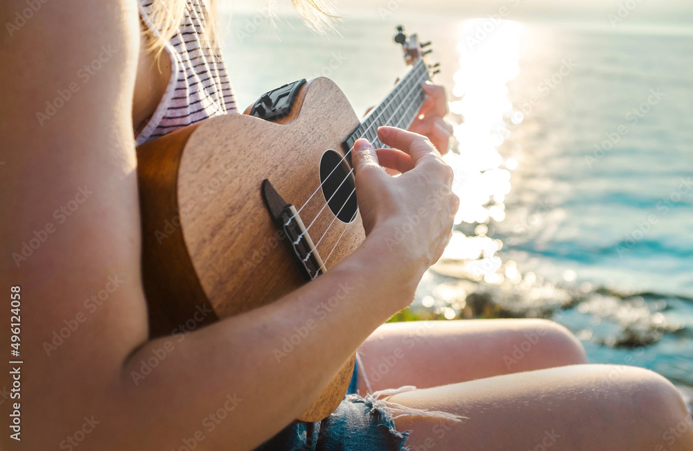 暑假，高加索女人在海滩上放松和玩尤克里里琴，如此快乐和奢华