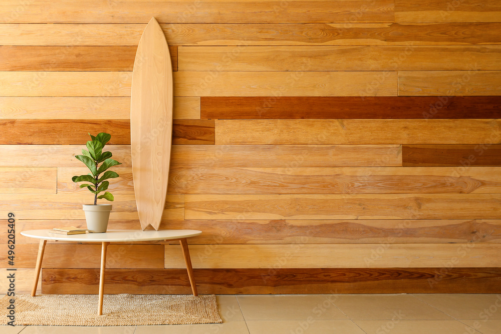 木墙上有冲浪板、室内植物和书籍的桌子
