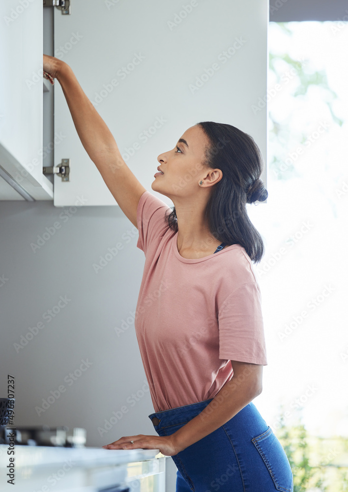 成年人意味着你要打扫卫生。一张年轻女子打扫厨房橱柜的照片。